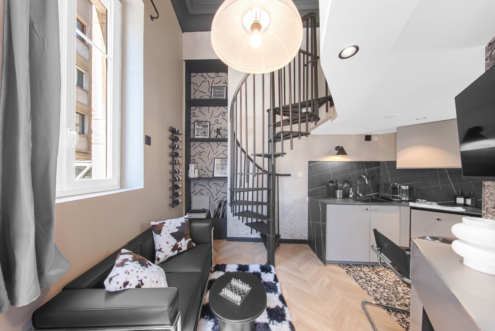 Espace salon du Loft d'Artiste avec cuisine équipée et escalier en colimaçon