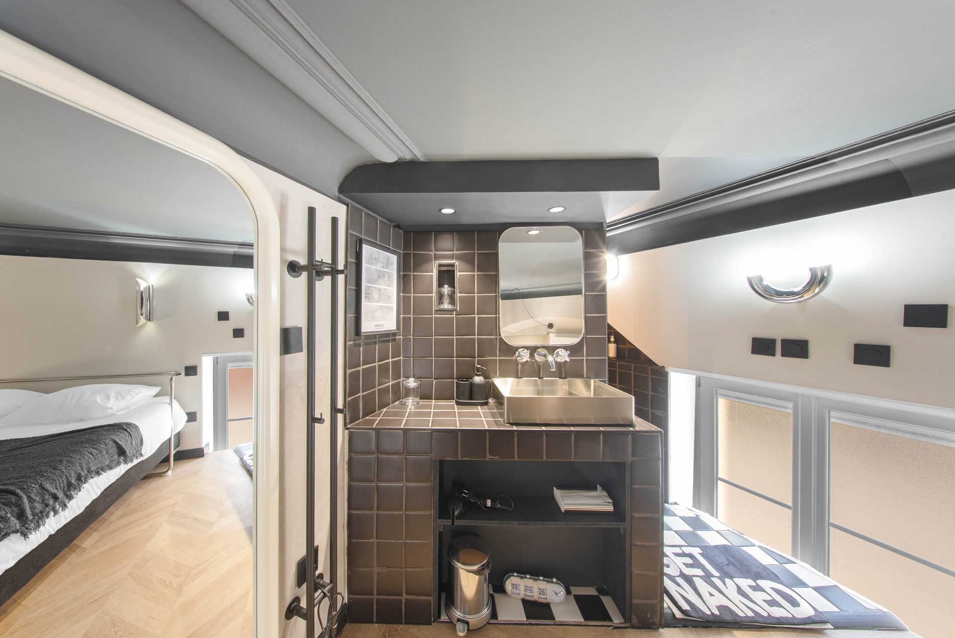 Salle d'eau en mezzanine avec vasque inox et carrelage brun
