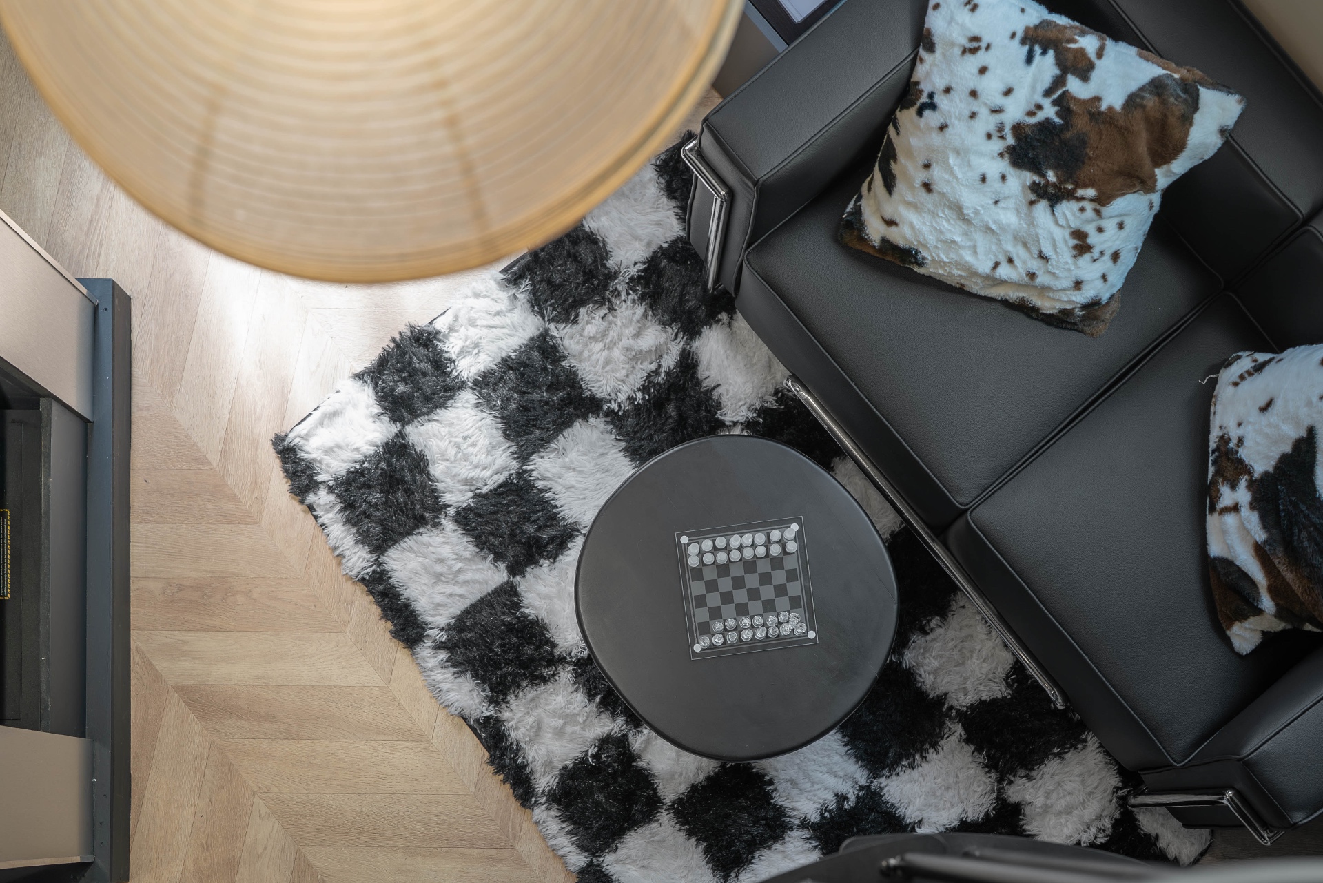 Vue plongeante sur le salon : tapis damier, fauteuil Le Corbusier et échiquier
