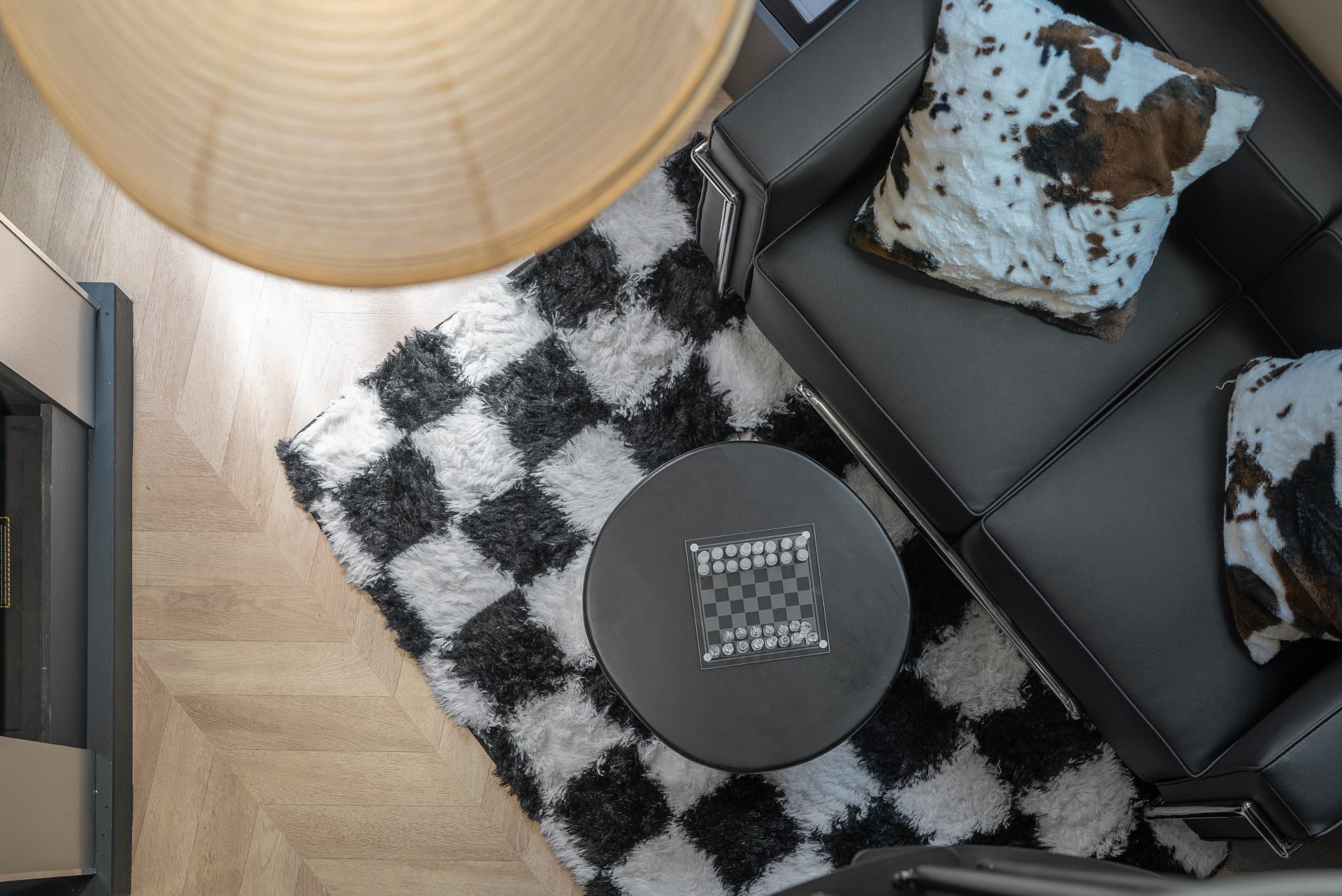 Vue plongeante sur le salon : tapis damier, fauteuil Le Corbusier et échiquier